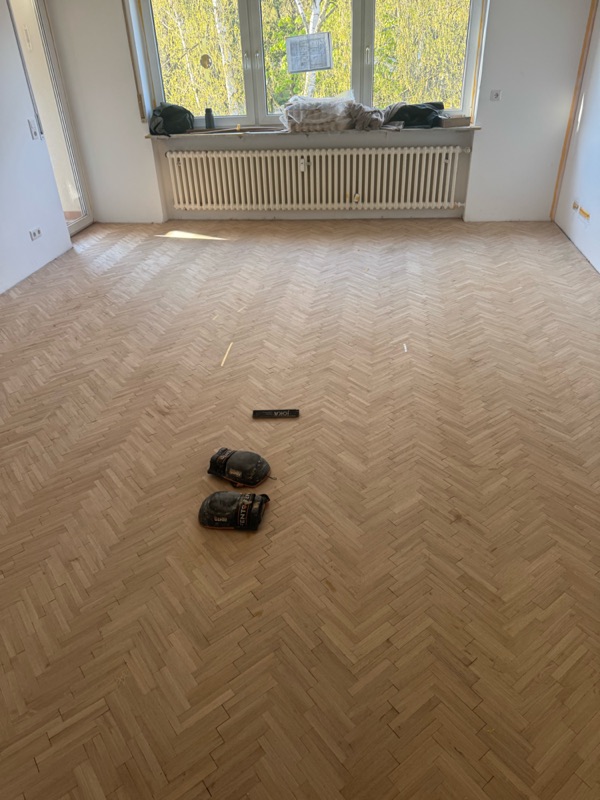 Komplett verlegtes rohes Eichen-Fischgrätparkett im Wohnzimmer mit Fensterfront