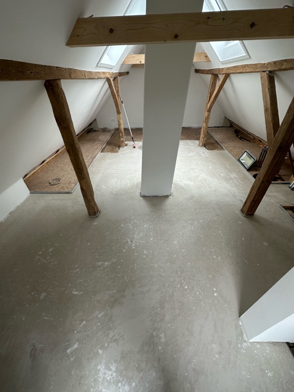 Dachgeschoss mit freigelegten Holzbalken und vorbereitetem Estrich