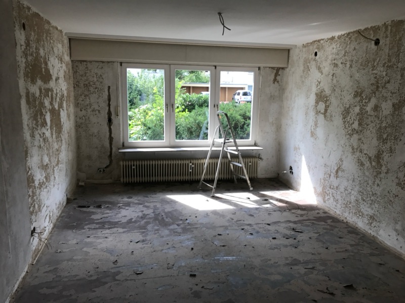 Zimmer im Rohzustand mit Fenster, Heizkörper und abgeschlagenem Wandputz