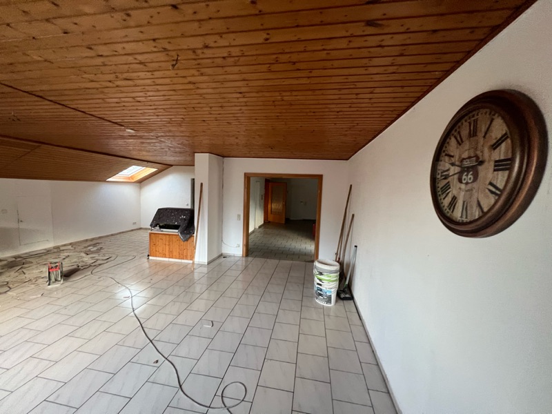 Dachgeschosszimmer mit Holzdecke und altem Fliesenboden vor dem Umbau