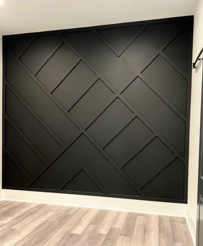Schwarze Akzentwand mit geometrischem Holzleistenmuster