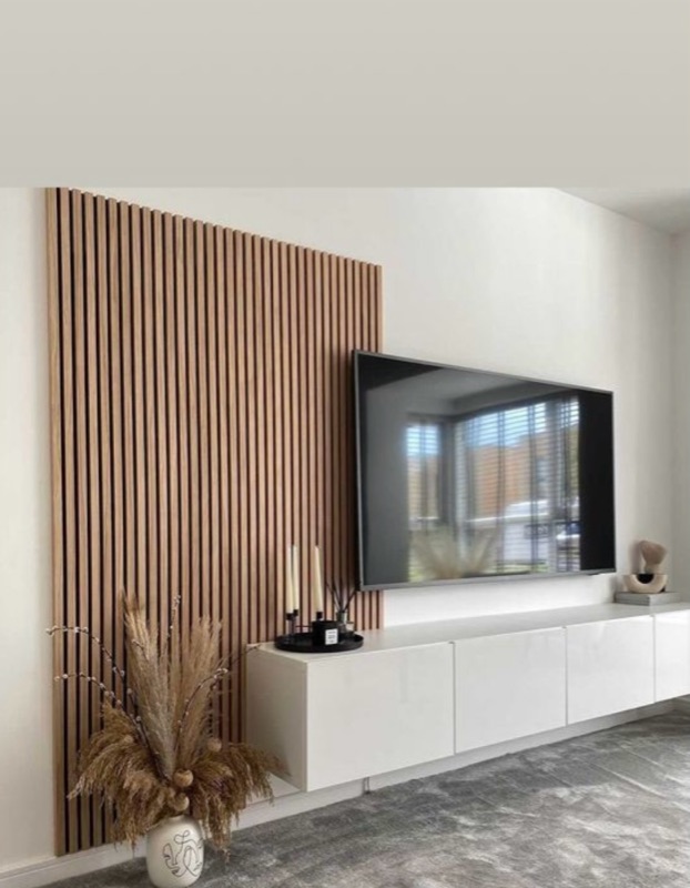 Akustikpaneel aus Holzlamellen hinter Fernseher mit weißem Lowboard