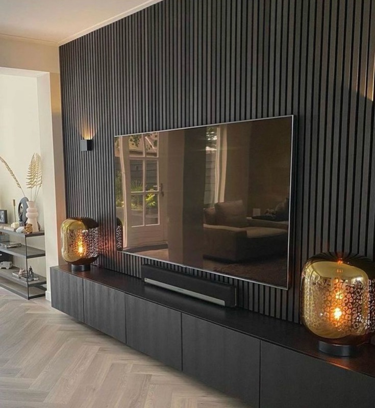 Schwarze Lamellenwand mit Fernseher und Fischgrätparkett im Wohnzimmer