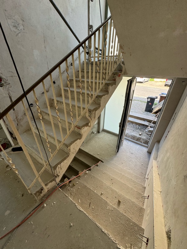 Blick von oben auf entkernte Treppe mit altem Metallgeländer