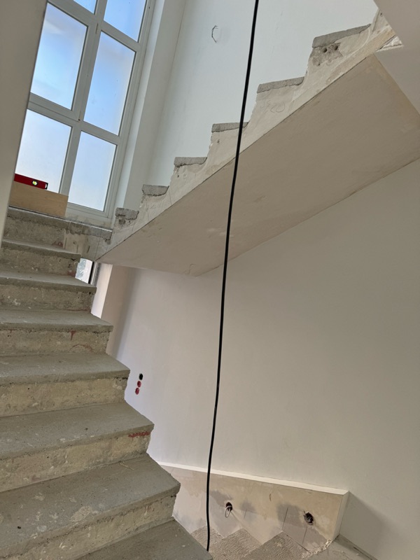 Rohe Betonstufen und frisch verputzte Wände im Treppenhaus