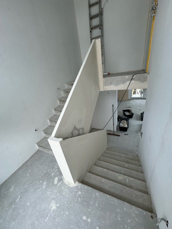 Verspachtelte weiße Treppenbrüstung mit rohen Betonstufen von oben