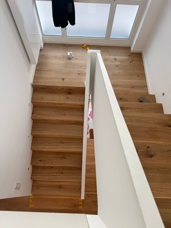 Blick von oben auf neue Eichenstufen mit weißer Brüstung
