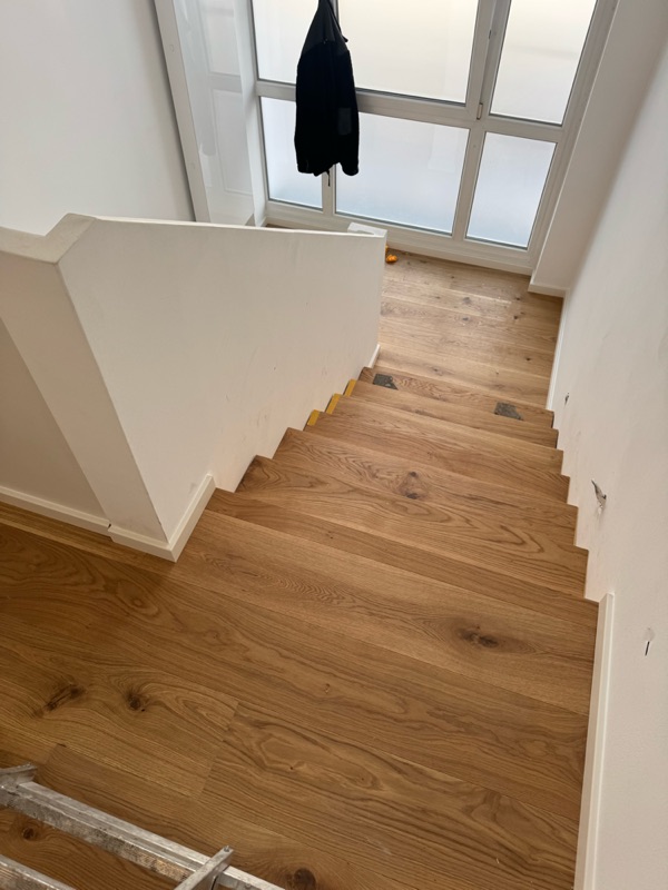 Fertig renovierte Treppe mit Eichenstufen und Parkettboden im Flur