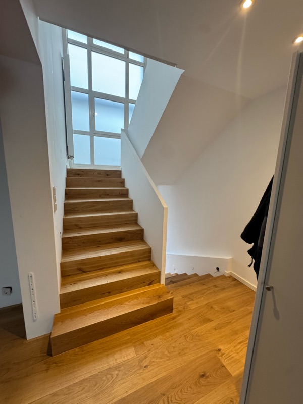 Fertige Eichenholztreppe mit weißer Brüstung und großem Sprossenfenster