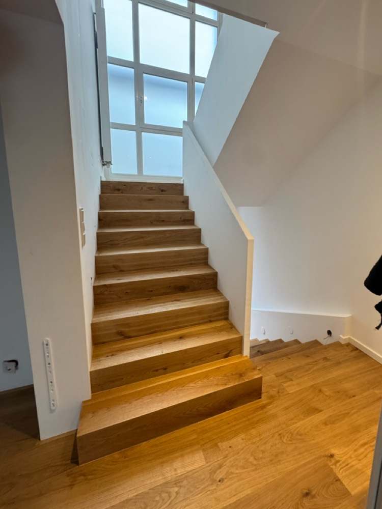 Dieselbe Treppe mit neuen Eichenstufen und weißer Brüstung nach der Renovierung