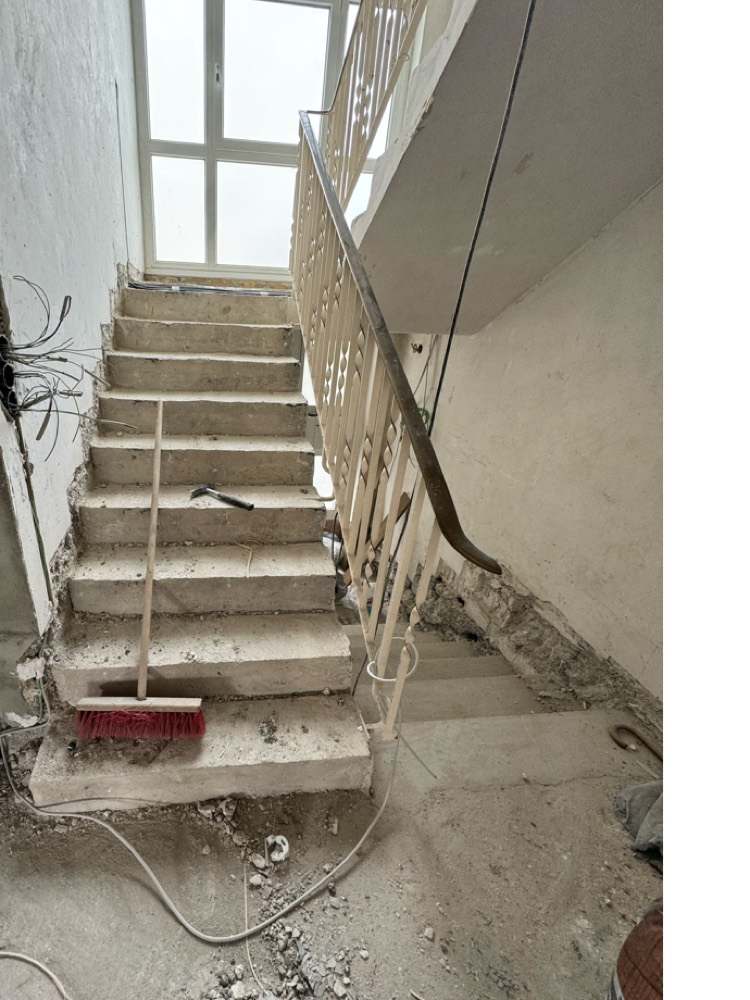 Rohe Betontreppe mit altem Geländer und Bauschutt vor der Renovierung
